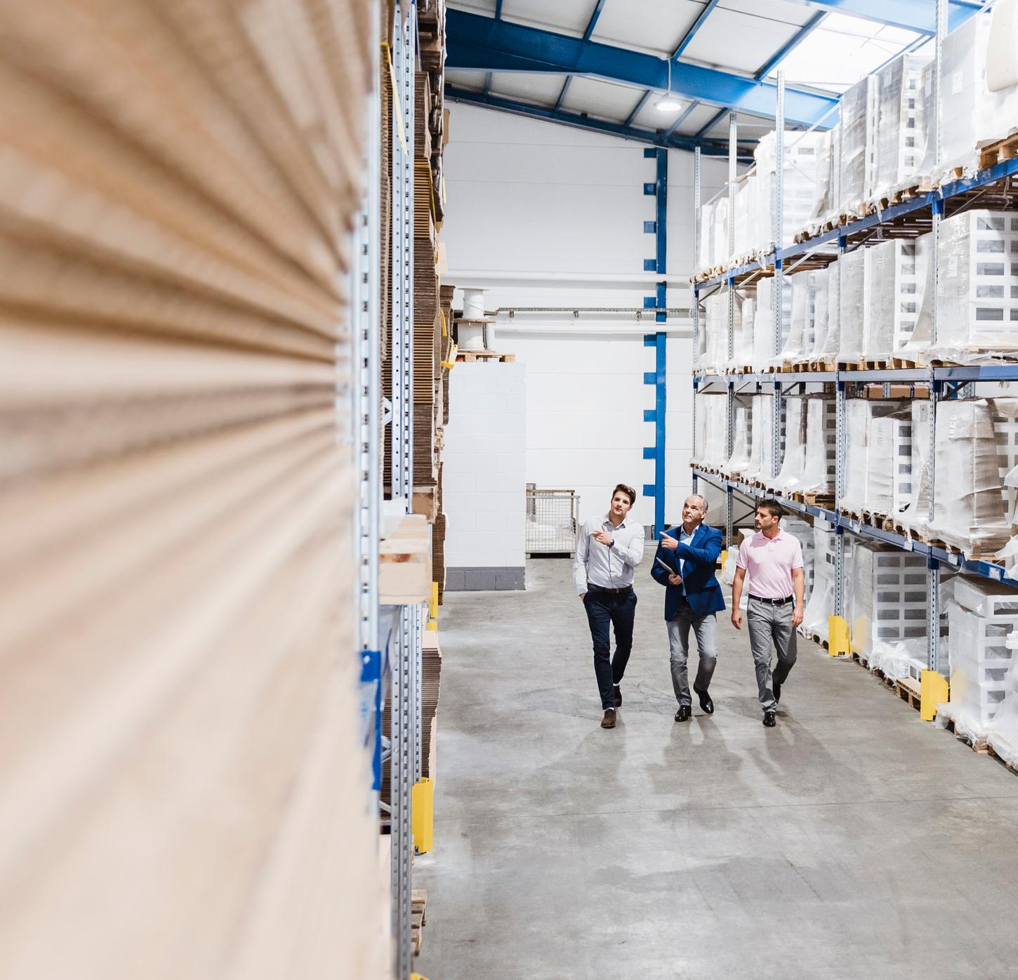 Three colleagues walking down a warehouse aisle